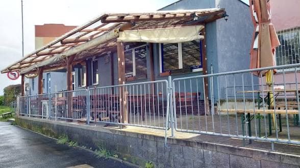 Venkovní terasa s dřevěným zastřešením, stoly a židlemi před budovou U Velblouda